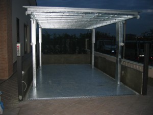 Elevatore per auto a comando elettrico con movimentazioni oleodinamiche per traslazione di autovetture tra piani definiti a pantografo con coperchio di chiusura fossa