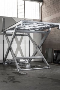 Elevatore per auto a comando elettrico con movimentazioni oleodinamiche per traslazione di autovetture tra piani definiti a pantografo senza coperchio di chiusura fossa